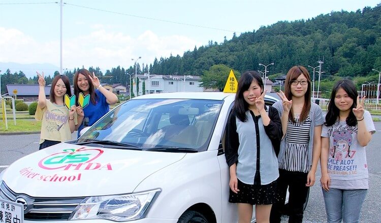 飯田自動車学校の教習車の前で