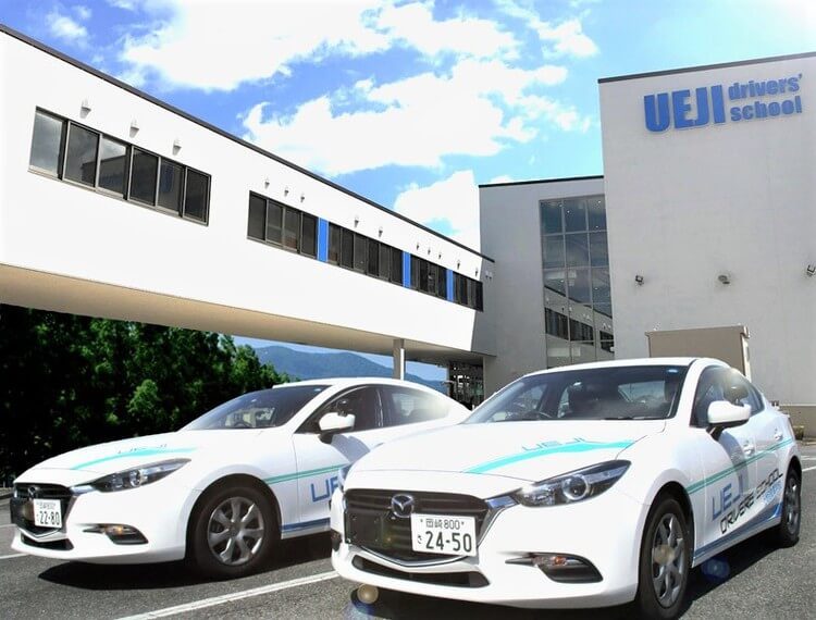 上地自動車学校の校舎前の合宿生と教習車